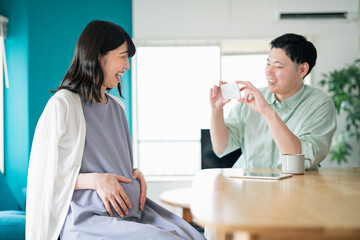 Fototapeta premium 妊娠中の妻の写真を撮る夫