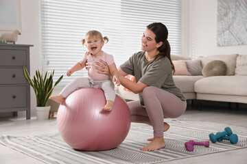 Mother doing exercise with her daughter on fitball at home