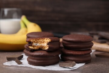 Tasty banana choco pies and pieces of chocolate on textured table, closeup