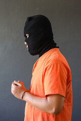 Side view of a prisoner in orange t-shirt wearing handcuff isolated over grey background