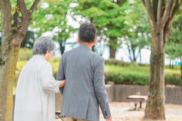 公園を歩くシニア・高齢者夫婦（後ろ姿）
