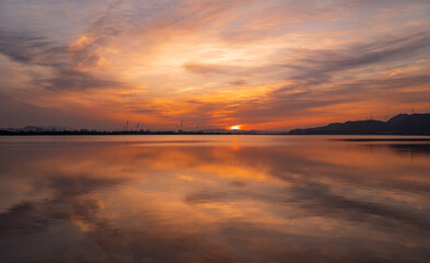 Fototapeta na wymiar 朝日の写真。手前の湖に映る雲の陰影がきれいです