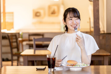 カフェでランチ・昼食にハンバーガーを食べる女性

