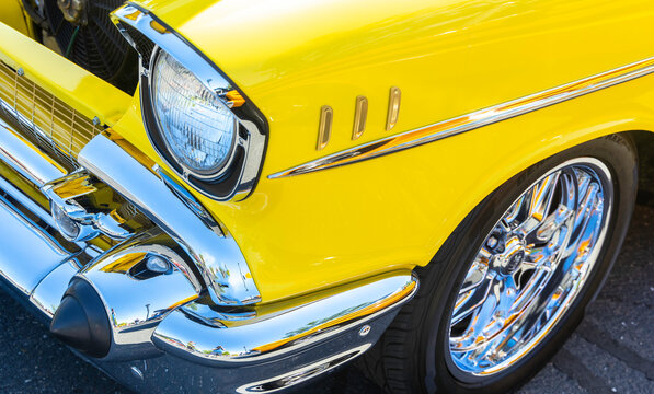 Close-up of the headlight from a restored vintage classic custom yellow car with chrome