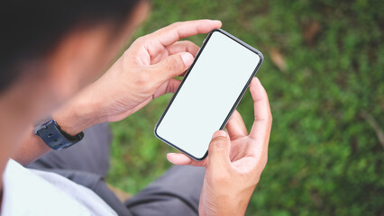 Over shoulder view of young man holding smart phone with blank screen..