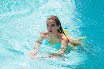 Fototapeta na wymiar Fashion woman in luxury pool. Elegant sexy woman in the white bikini on tanned slim body posing near swimming pool. Rich summer rest.