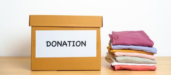 Donation, Charity, Volunteer, Giving and Delivery Concept. Clothes with Donation box at home or office for support and help poor, refugee and homeless people. Copy space for text