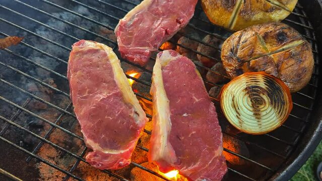 Flame grilled steaks and mushrooms over the hot coals with bursts of fire and smoke.