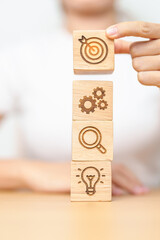 Woman hand holding dartboard above Gear, magnifying and Lightbulb icon block. business planning...