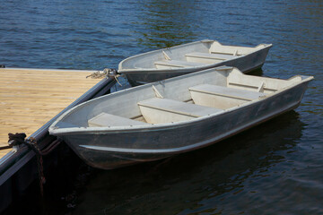two rowboats on the edge of a dock on a calm lake aluminum boats recreation