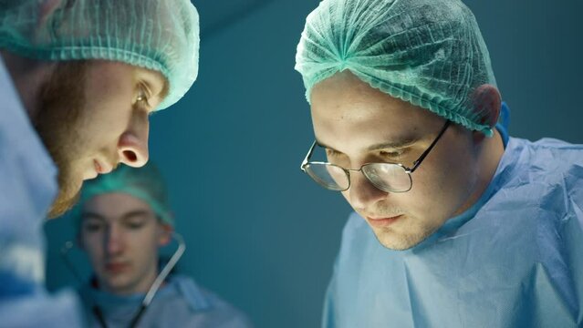 Close up portrait of serious focused vet doctor during surgery operation in veterinary clinic. Vets doing surgery operation for pet in veterinary clinic 4K. Portraits of two concentrated male surgeons