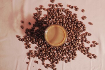 Cup of coffee with and coffee beans on peach color background. Creative layout. Breakfast concept. Top view, flat lay