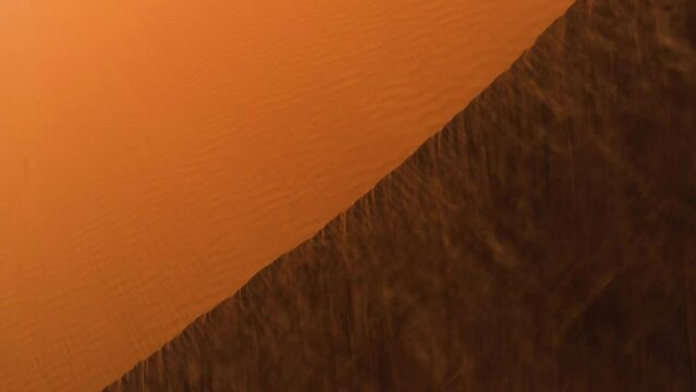 Aerial view of wind dusting sand over dunes in the Namib desert, in sunny Namibia