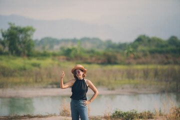 Fototapeta na wymiar beautiful asian woman standing on open land scape and raising right thumb with good feeling