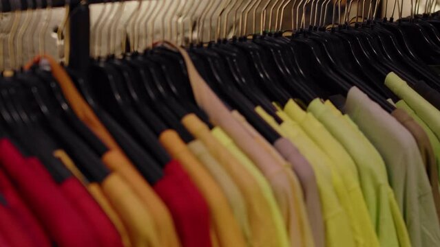 Fashion clothes on clothing rack - bright colorful closet. Closeup of rainbow color choice of trendy female wear on hangers in store closet or spring cleaning concept