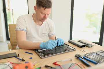 Master carefully fixes detail of broken laptop in workshop