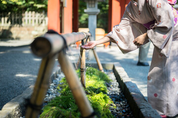 神社の手水で手を清める着物を着た女性のクローズアップ