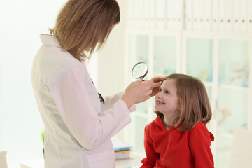 Optometrist examining little girl eye in doctor premise