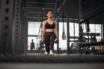 Fototapeta na wymiar Strong Asian woman doing lunge exercise with kettlebell at cross fit gym. Athlete female wearing sportswear workout on grey gym background with weight and dumbbell equipment. Healthy lifestyle.