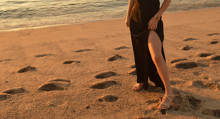 legs of a woman in a dress on the beach at sunset