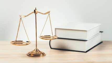 Shiny golden balanced scale and law book on desk in law school as concept justice and legal symbol....
