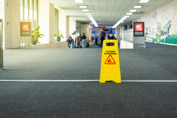 Signs cleaning in process yellow plastic on floor at international airport terminal