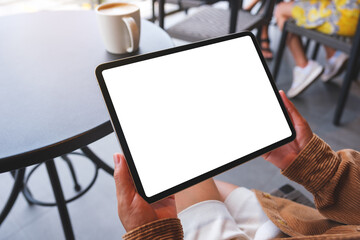 Mockup image of a woman holding digital tablet with blank white desktop screen in cafe