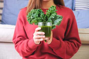 Closeup image of a young woman holding kale leaves and kale smoothie - obrazy, fototapety, plakaty