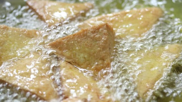 Close-up of deep frying tofu in boiling oil. vegan and vegetarian food