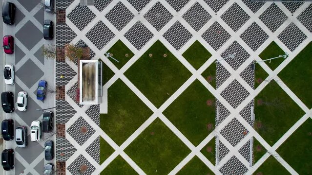 Top-down view of Paved plaza with contemporary geometric brick patterns, road with cars, woonerf, and people walking