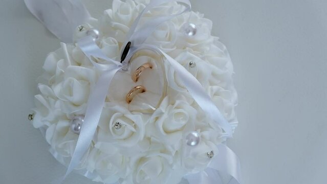 Closeup of flower bouquet pillow with golden rings inside, wedding celebration
