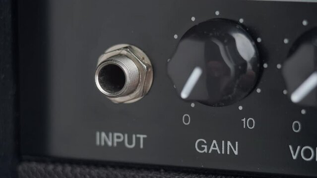 A man's hand plugging electric guitar cable to the amplifier. Close up