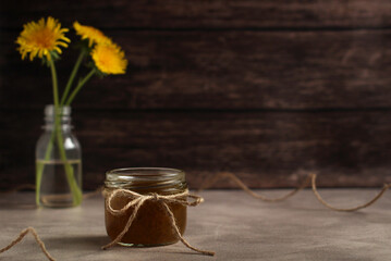 Dandelion flower jam in a glass jar on a wooden background