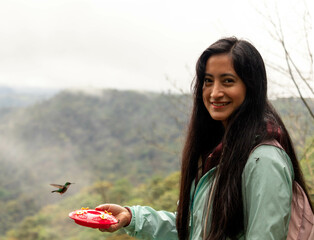 mujer soven sonriendo observando aves de colores colibries © Lenin