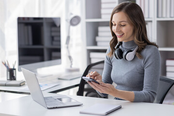 Young adult happy smiling Hispanic Asian student wearing headphones talking on online chat meeting using laptop in university campus or at virtual office. College female student learning remotely.
