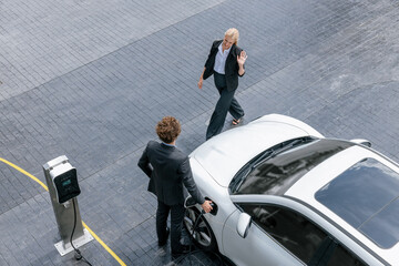 Aerial view progressive lifestyle of businesspeople with electric car connected to charging station...