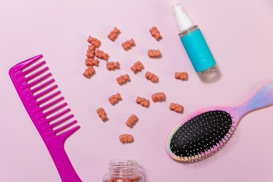 Hair care items and hair vitamin gummies on a pink background