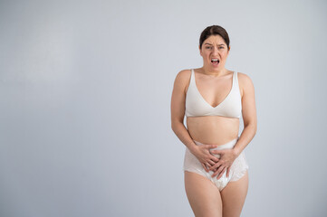 A woman in adult diapers holds her hands on her stomach. Urinary incontinence problem.