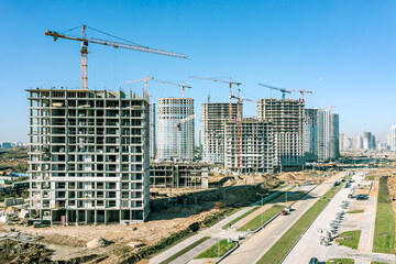 large construction site of new high-rise apartment buildings with cranes against blue sky. drone photography.