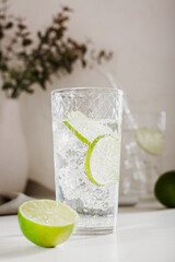 Close up of mineral water with ice and lime in a glass for refreshment in the summer vertical view