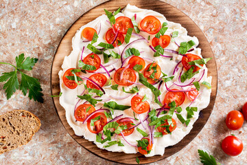 Close up of Homemade butter board with tomatoes, red onions and herbs and baguette pieces top view