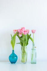 Fototapeta na wymiar Pink tulips bouquet in glass vase on white background copy space
