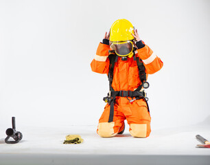 Professional firefighter is sitting and kneeling down attempting to put on a yellow helmet for his own safety.