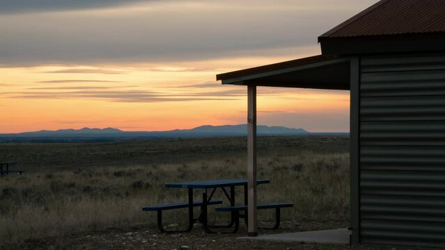 Time lapse of sunset over mountains and prairie cabin 