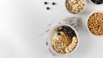 Homemade granola with Greek yogurt, almonds, blueberries and banana in a bowl. Copy space