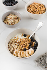 Homemade granola with Greek yogurt, almonds, blueberries and banana in a bowl. 