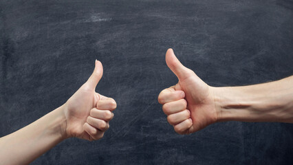Like gesture. Approval sign. Man and woman hands showing thumb up on chalkboard background.