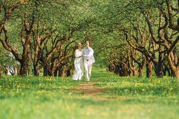 Happy newlyweds hold hands of each other and dancing in the park