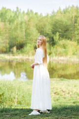 Fototapeta na wymiar Full length portrait of young woman in long dress on river bank