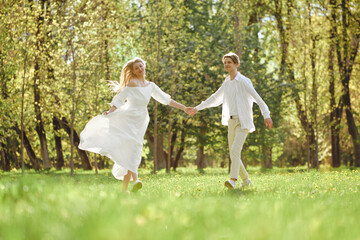 Naklejka na ściany i meble Happy newlyweds holding hands and dancing on the lawn